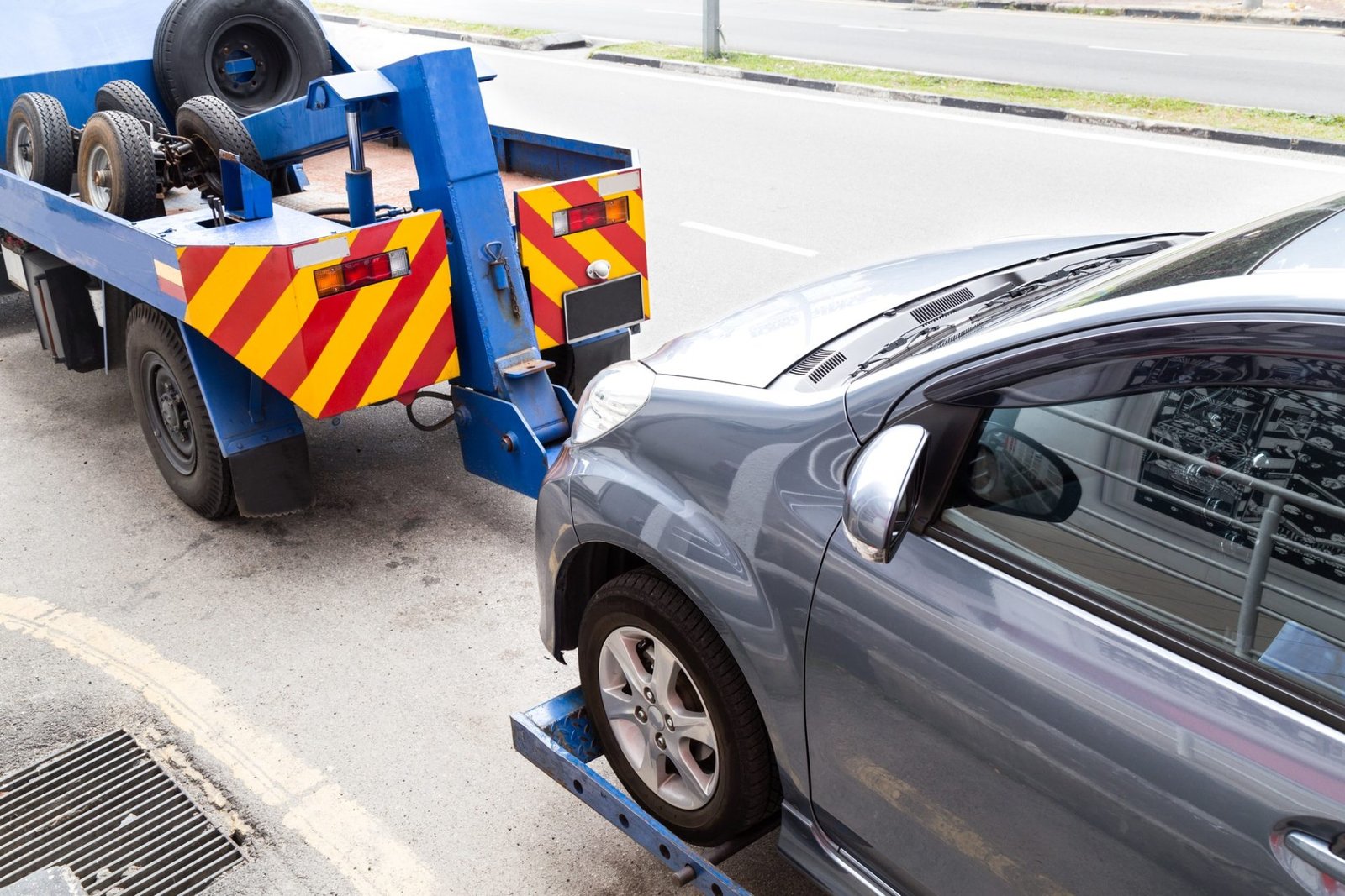tow-truck-towing-a-broken-down-car-on-the-street-e1632464126501