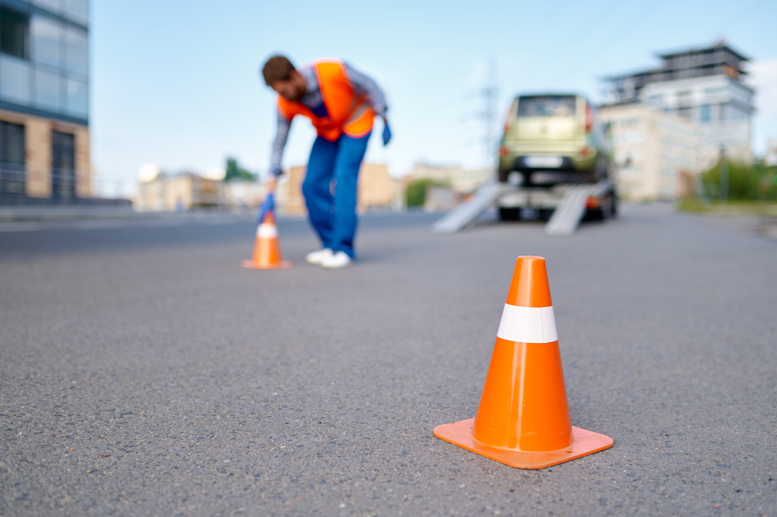 driver setting safety cones while loading vehicle onto car transporter