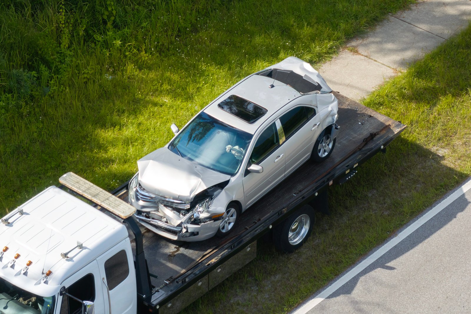 Accident-damaged silver car on a tow truck – car recovery West Lothian