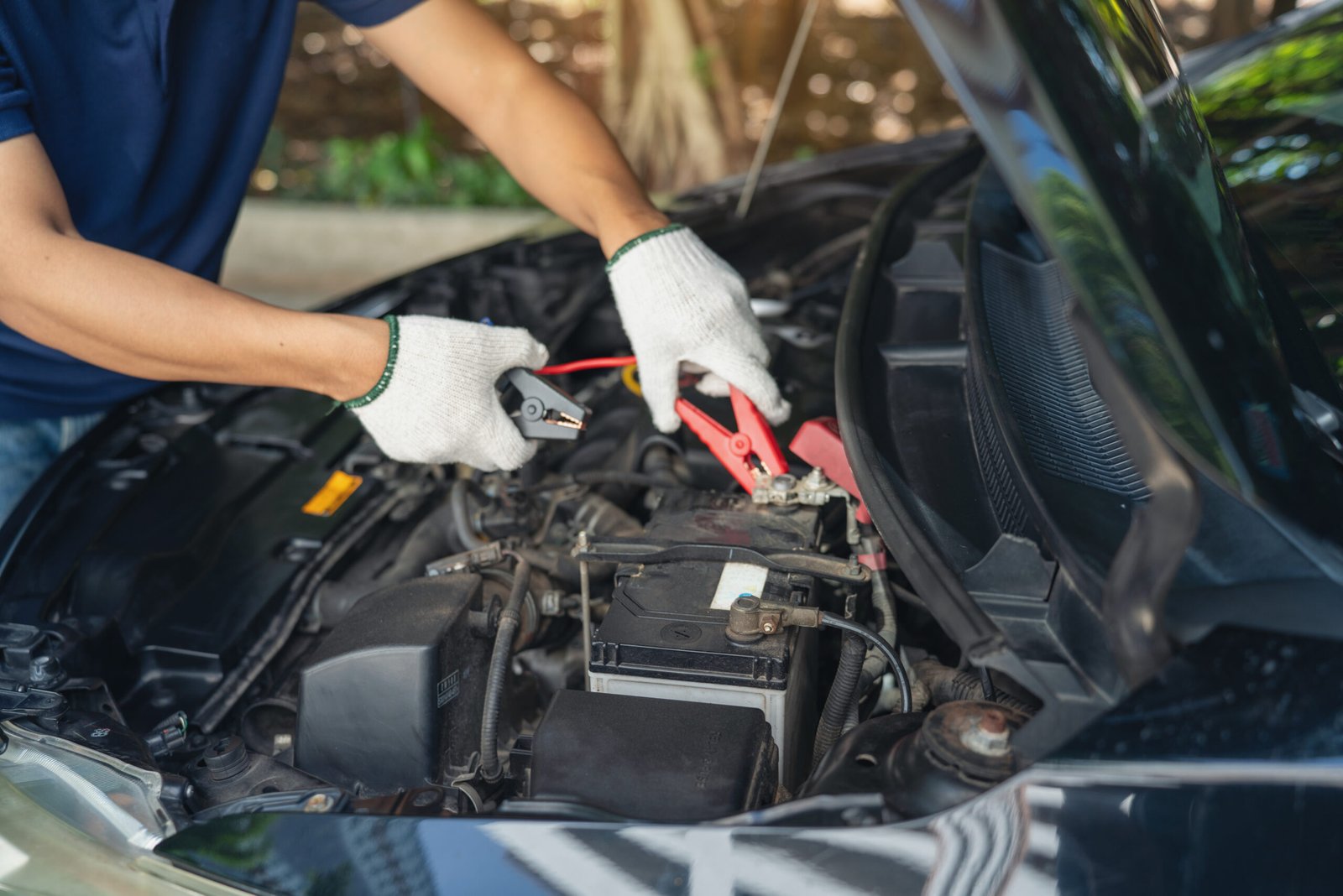 Roadside assistance East Calder – mechanic using jumper cables on a car engine